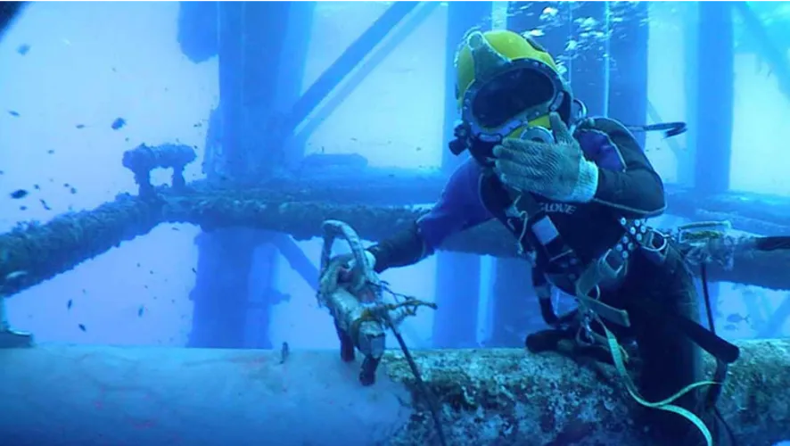 Professional divers cleaning an underwater ship hull